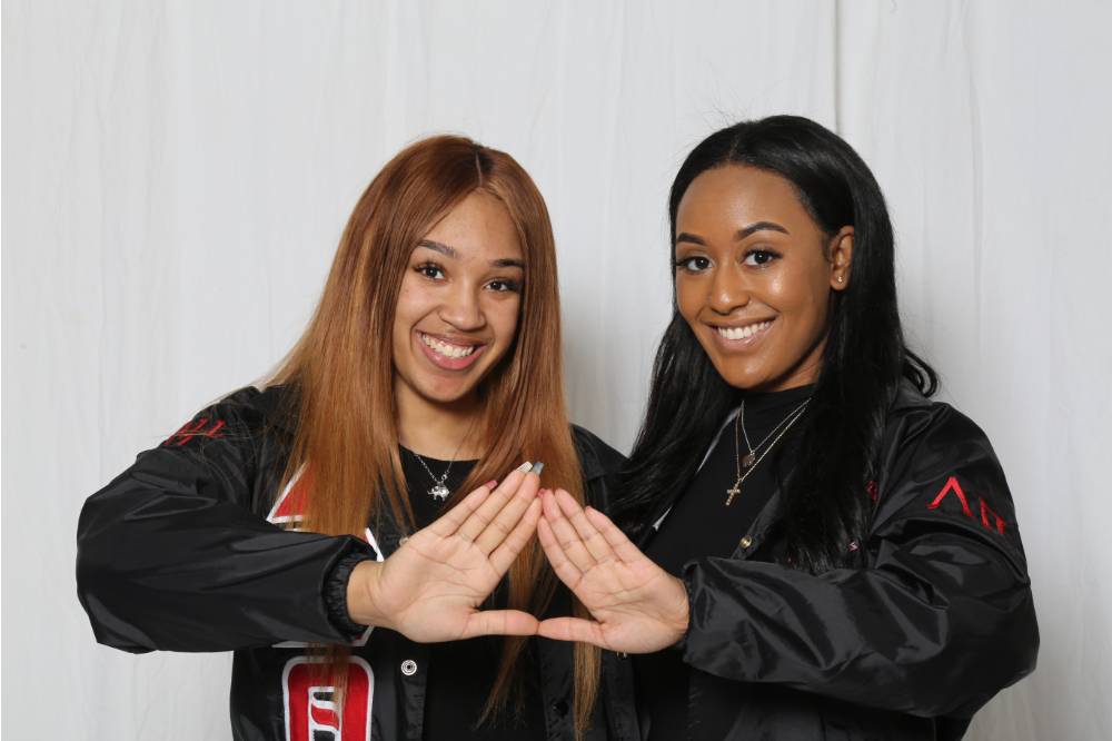two girls pose with hands in triangle